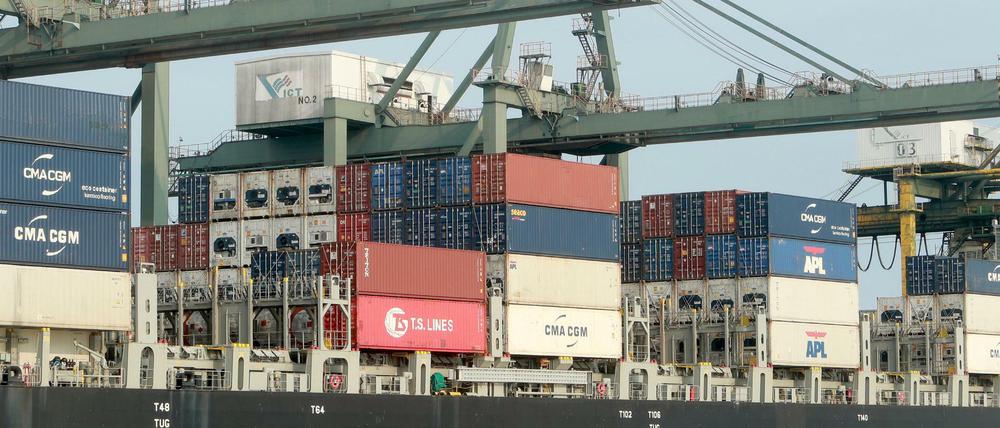 Container werden im Hafen auf ein Schiff verladen.