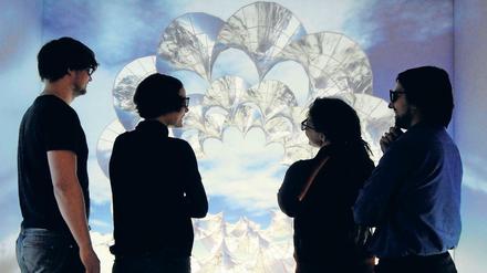 Vier wissenschaftliche Mitarbeiter:innen stehen vor einem 3-D-Modell einer Materialstruktur.