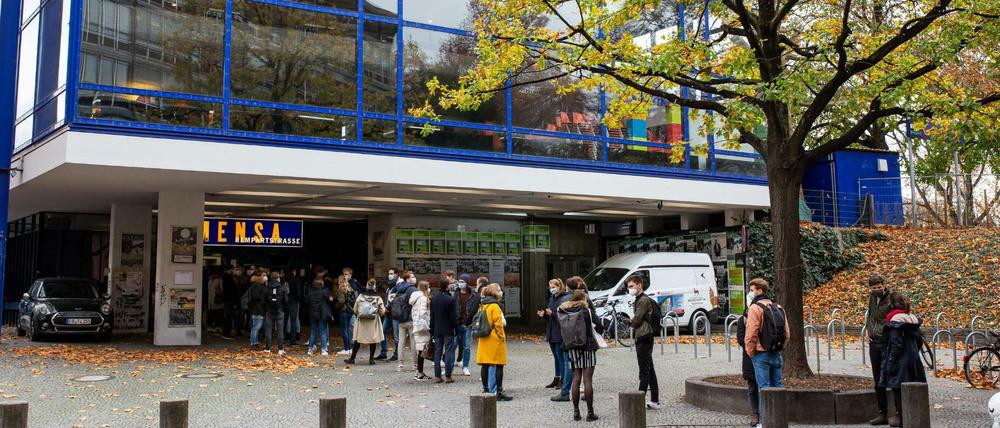 Studierende stehen vor einem modernen Mensagebäude Schlange.