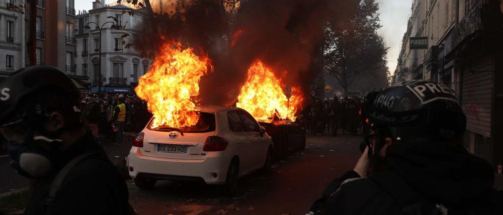 Zwei Autos brennen in Paris während der Demonstration gegen das umstrittene Sicherheitsgesetz.
