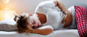 Eine Frau, die sich vor Menstruationsschmerzen krümmt - eben kein normales Bild. Denn oft steckt Endometriose dahinter.