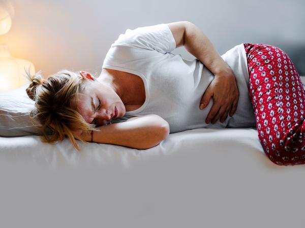 Eine Frau, die sich vor Menstruationsschmerzen krümmt - eben kein normales Bild. Denn oft steckt Endometriose dahinter.
