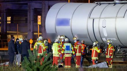 Rettungskräfte und Ermittler stehen neben den abgedeckten Leichen.