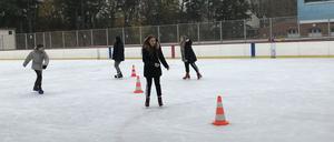Im Eisstadion üben Schülerinnen und Schüler etwa das Slalomfahren um orangene Hütchen.