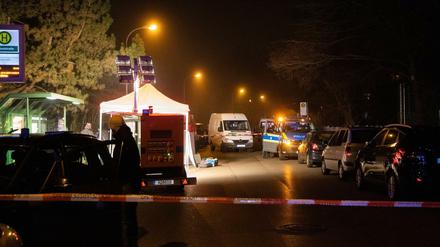 Polizeibeamte arbeiten am abgesperrten Tatort in der Nähe einer Haltestelle.