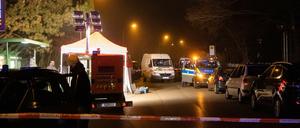 Polizeibeamte arbeiten am abgesperrten Tatort in der Nähe einer Haltestelle.