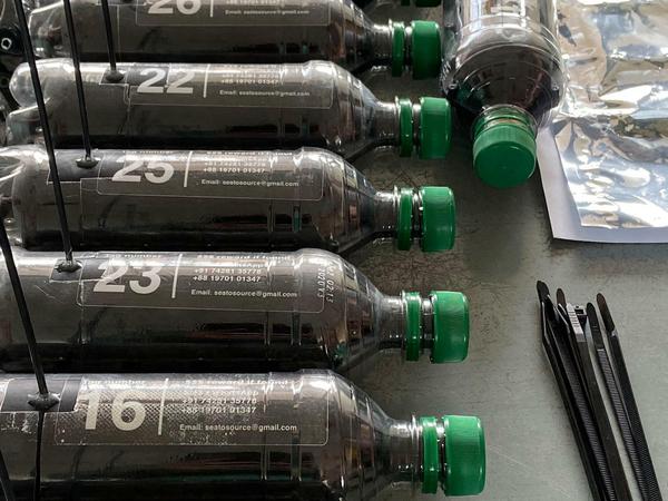 Sechs nummerierte, mit Sendern ausgestattete, Plastikflaschen mit grünen Deckeln liegen auf einem Tisch.