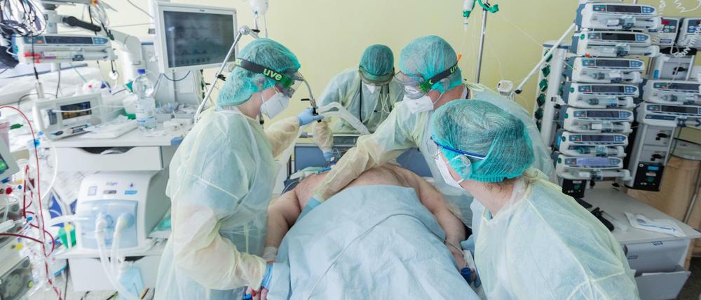 Intensivpflegekräfte versorgen einen Corona-Patienten, der beatmet auf einer Intensivstation liegt.