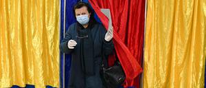 Eine Frau mit Mund-Nasen-Schutz verlässt eine Wahlkabine, nach der Stimmabgabe für die Parlamentswahlen in Rumänien. 