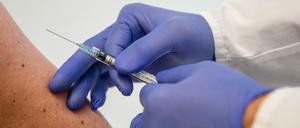 Ein Mann demonstriert im Institut für Tropenmedizin an der Uniklinik Tübingen, wie eine Frau geimpft wird.