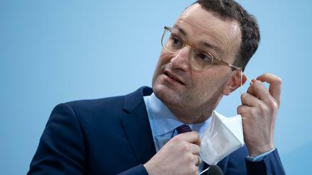 Jens Spahn nimmt seine FFP-2-Maske vor einer Pressekonferenz in seinem Ministerium ab. 