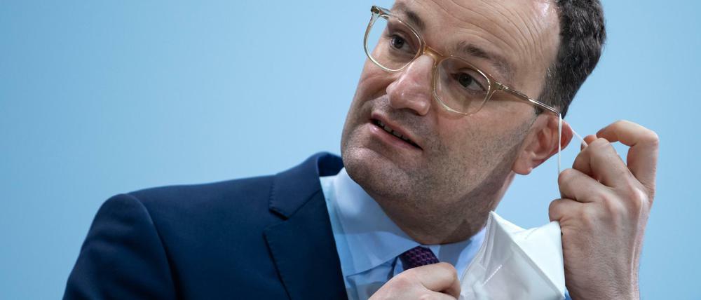 Jens Spahn nimmt seine FFP-2-Maske vor einer Pressekonferenz in seinem Ministerium ab.