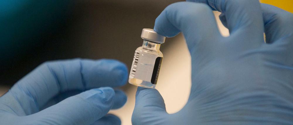 Ein Arbeiter hält eine Ampulle des Pfizer-BioNTech COVID-19-Impfstoffs in der Hand