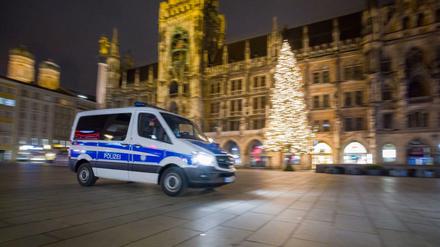 Ein Polizeiwagen fährt über den menschenleeren Marienplatz im Zentrum der Stadt.