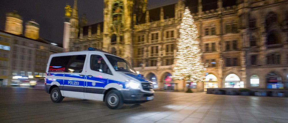 Ein Polizeiwagen fährt über den menschenleeren Marienplatz im Zentrum der Stadt.