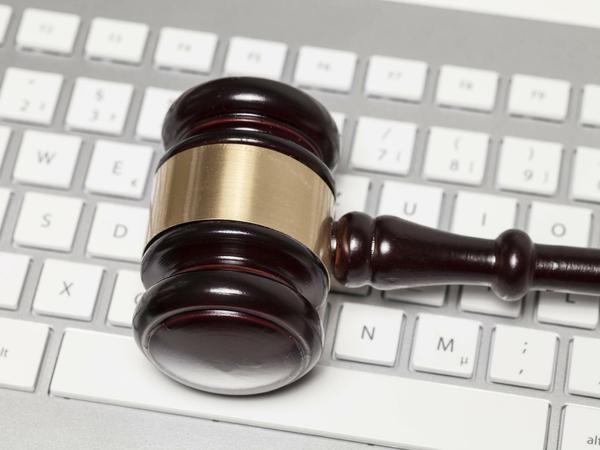 Ein Holzhammer, wie er bei Gericht zum Einsatz kommt, liegt auf einer Computertastatur.