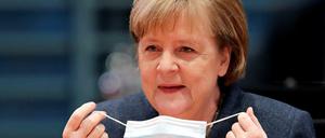 Bundeskanzlerin Angela Merkel nimmt ihre Maske ab.