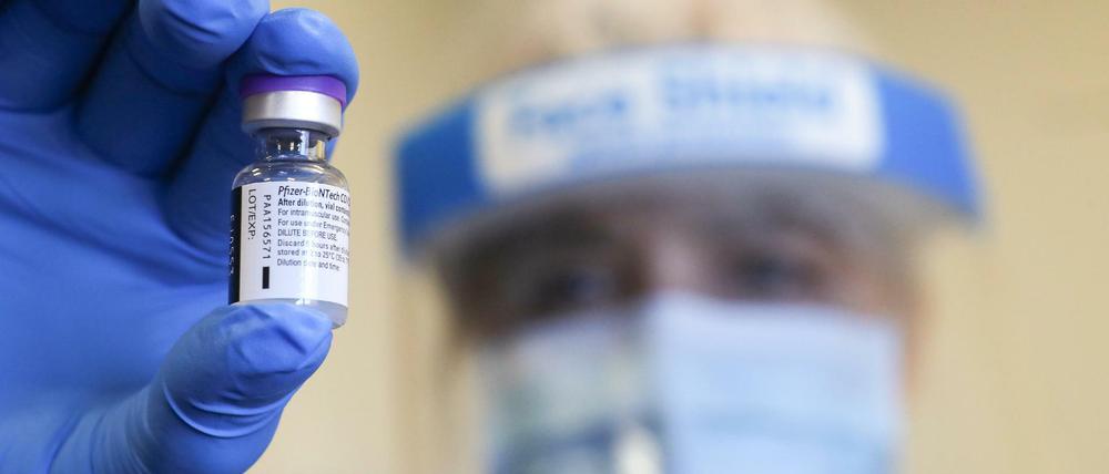 Ein Klinikmitarbeiter hält eine Dosis des Corona-Impfstoffs von Pfizer in der Hand.