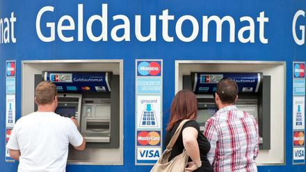 Kunden stehen in Berlin an Bankautomaten.