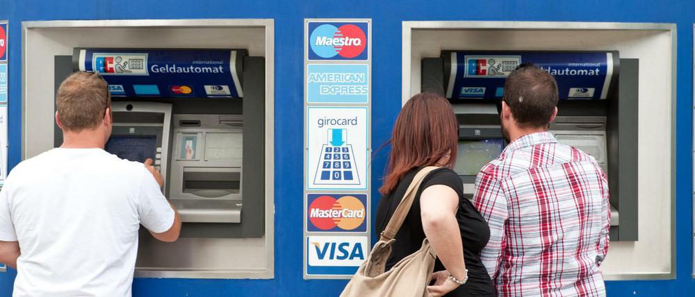 Kunden stehen in Berlin an Bankautomaten.