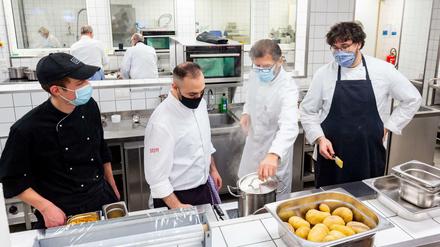 Abschmecken mit Mund-Nasen-Schutz. Ausbilder Josef Eder übt mit Lehrlingen in der Küche der Industrie- und Handelskammer.