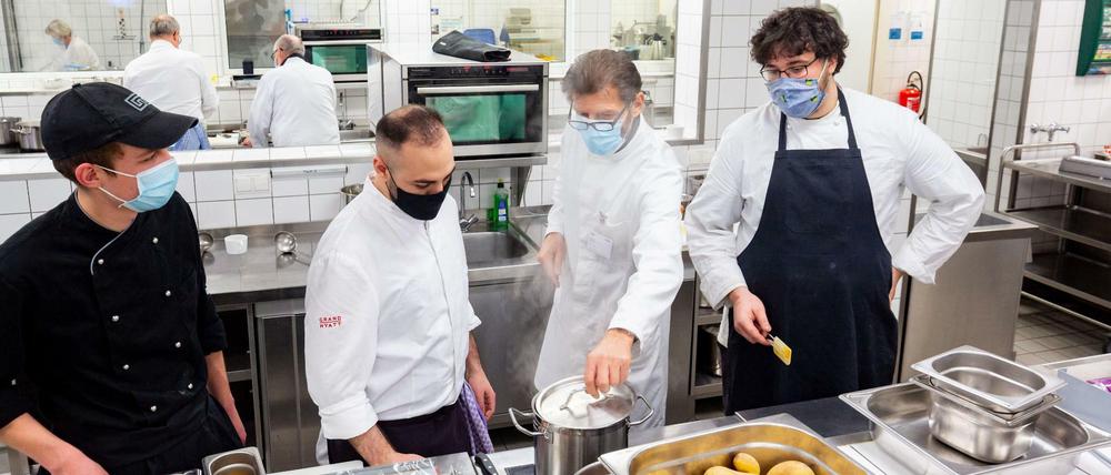 Abschmecken mit Mund-Nasen-Schutz. Ausbilder Josef Eder übt mit Lehrlingen in der Küche der Industrie- und Handelskammer.