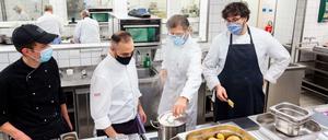 Abschmecken mit Mund-Nasen-Schutz. Ausbilder Josef Eder übt mit Lehrlingen in der Küche der Industrie- und Handelskammer.