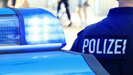 Beamter neben einem Polizeiauto (Symbolbild).