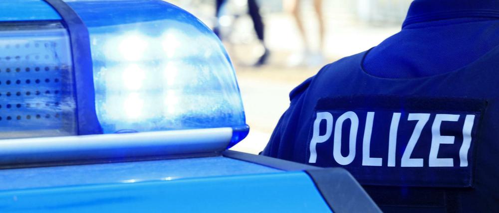 Beamter neben einem Polizeiauto (Symbolbild).