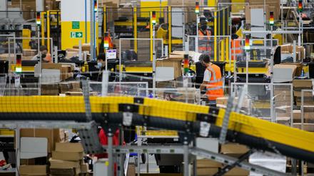 Mönchengladbach: Mitarbeiter mit Mund-Nasen-Bedeckung packen Pakete in einem Logistikzentrum des Versandhändlers Amazon.
