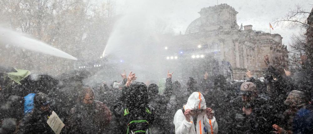 Die Polizei setzt bei einer Demonstration gegen die Corona-Einschränkungen der Bundesregierung am Brandenburger Tor unweit des Reichstagsgebäudes (hinten) Wasserwerfer ein.