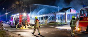 Feuerwehrleute löschen am Neujahrsmorgen einen brennenden Supermarkt in Buckow.
