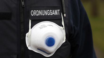Ein Mitarbeiter des Ordnungsamts trägt einen Mundschutz an seiner Weste.