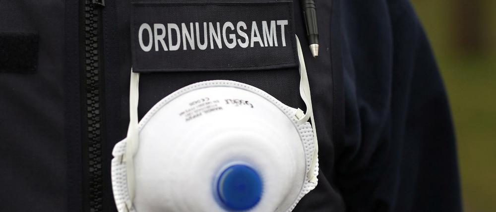 Ein Mitarbeiter des Ordnungsamts trägt einen Mundschutz an seiner Weste.