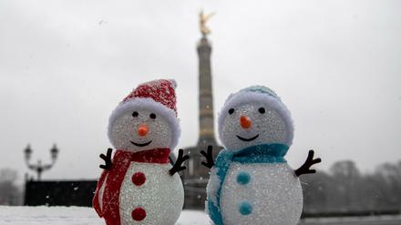 Auf einer Mauer vor der Siegessäule stehen zwei Schneemännchen-Puppen. 