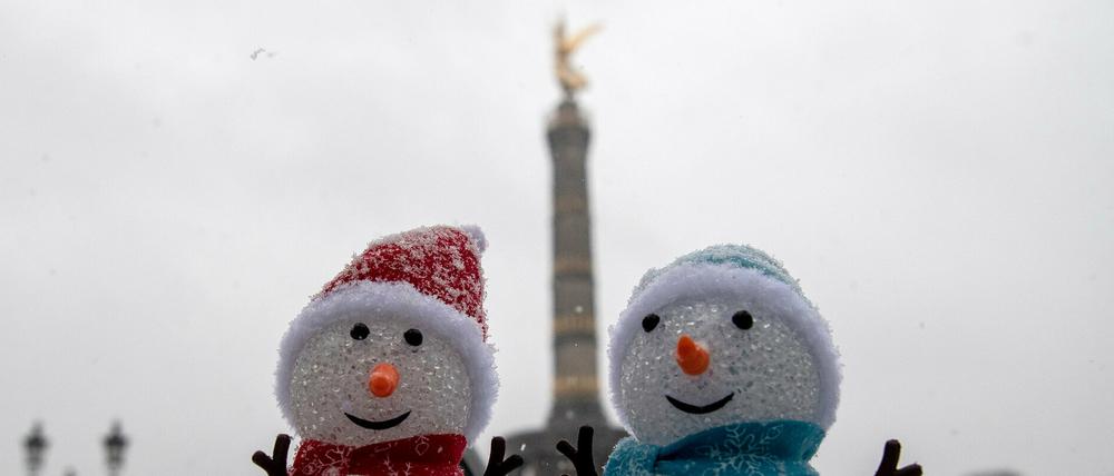 Auf einer Mauer vor der Siegessäule stehen zwei Schneemännchen-Puppen.