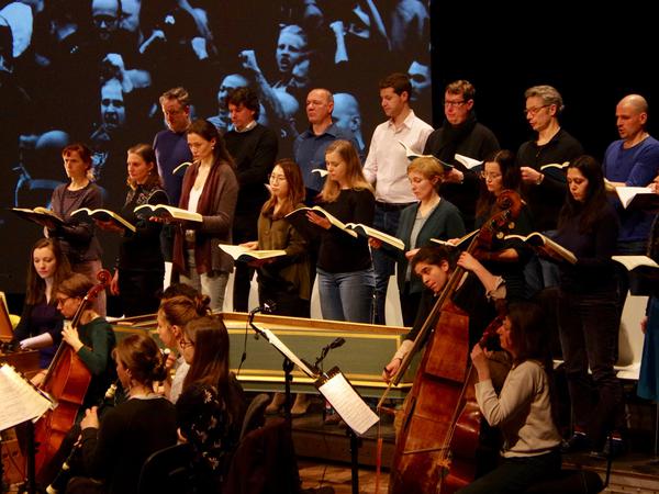 Das Vocalconsort Berlin spielt die Johannespassion. Im Hintergrund ist eine Projektion rechter Demonstranten in Chemnitz zu sehen.