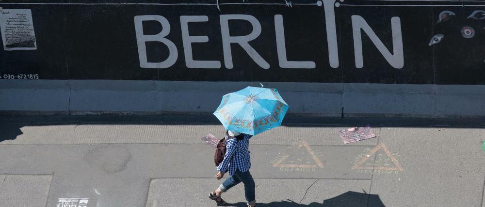 Eine Touristin nutzt einen Regenschirm als Schutz gegen die Sonne an der East Side Gallery im Juni 2019.