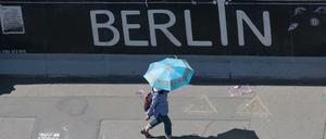 Eine Touristin nutzt einen Regenschirm als Schutz gegen die Sonne an der East Side Gallery im Juni 2019.
