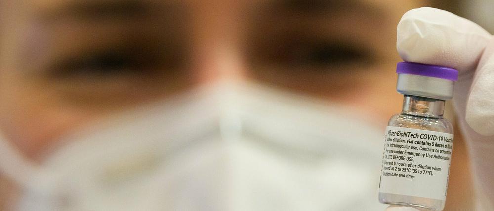 Eine Ärztin hält ein Dosis des Pfizer-Biontech-Impfstoffes gegen Covid-19 zwischen den Fingern.