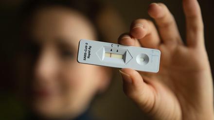 Eine junge Frau hält einen negativen Corona-Schnelltest in der Hand.