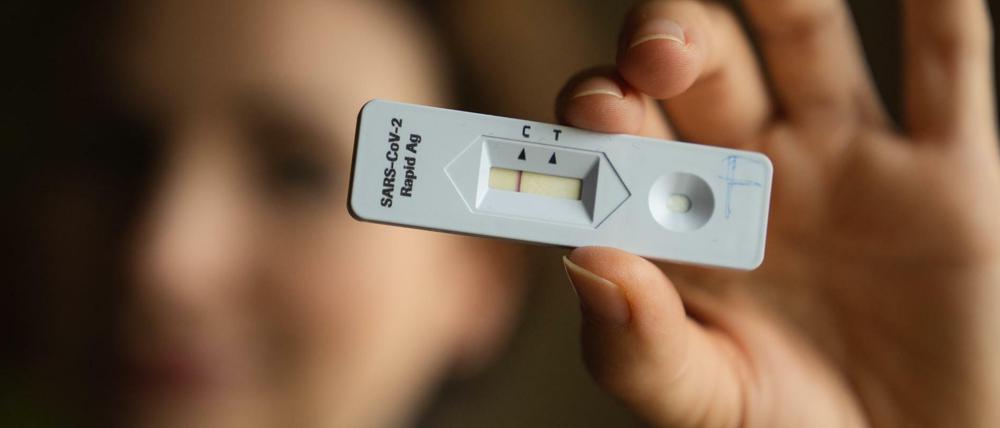 Eine junge Frau hält einen negativen Corona-Schnelltest in der Hand.