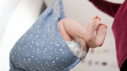 Eine Hebamme wiegt im Rahmen der Nachsorge ein Baby - zugegeben, eine gestellte Szene.