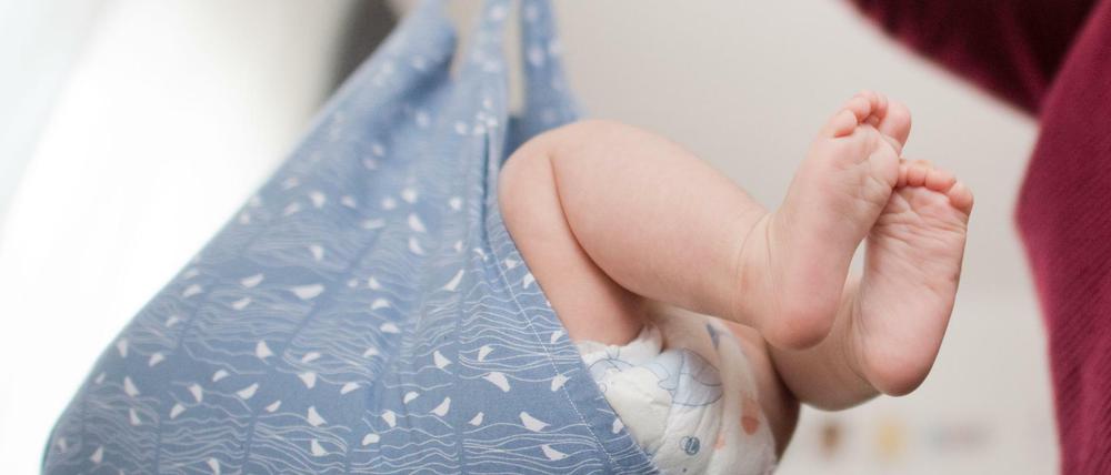 Eine Hebamme wiegt im Rahmen der Nachsorge ein Baby - zugegeben, eine gestellte Szene.