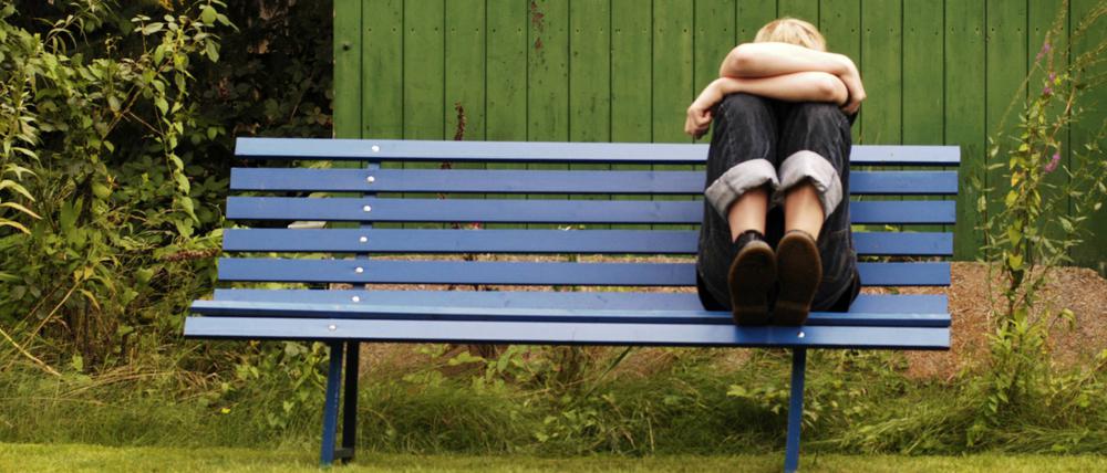 Frustrierter Jugendlicher auf einer Parkbank.