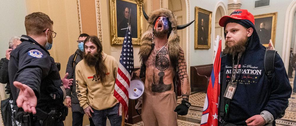 Unterstützer von US-Präsident Trump stehen vor Polizeibeamten auf dem Gang vor der Senatskammer im Kapitol in Washington.