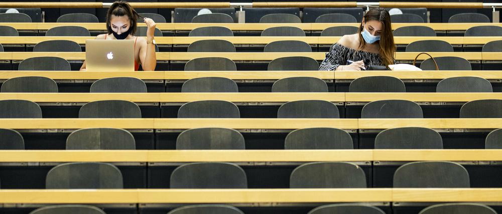 Studentinnen mit Mund-Nasen-Schutz sitzen in einem Hörsaal einer Universität.