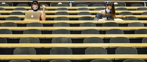 Studentinnen mit Mund-Nasen-Schutz sitzen in einem Hörsaal einer Universität.