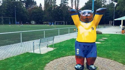 Bärenfigur in gelb-blauen Vereinsfarbem am Sportplatz der Sportfreunde in Berlin-Kladow.