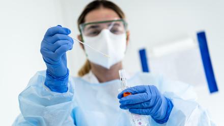 Laborantin mit Mund- und Körperschutz analysiert Coronatest.